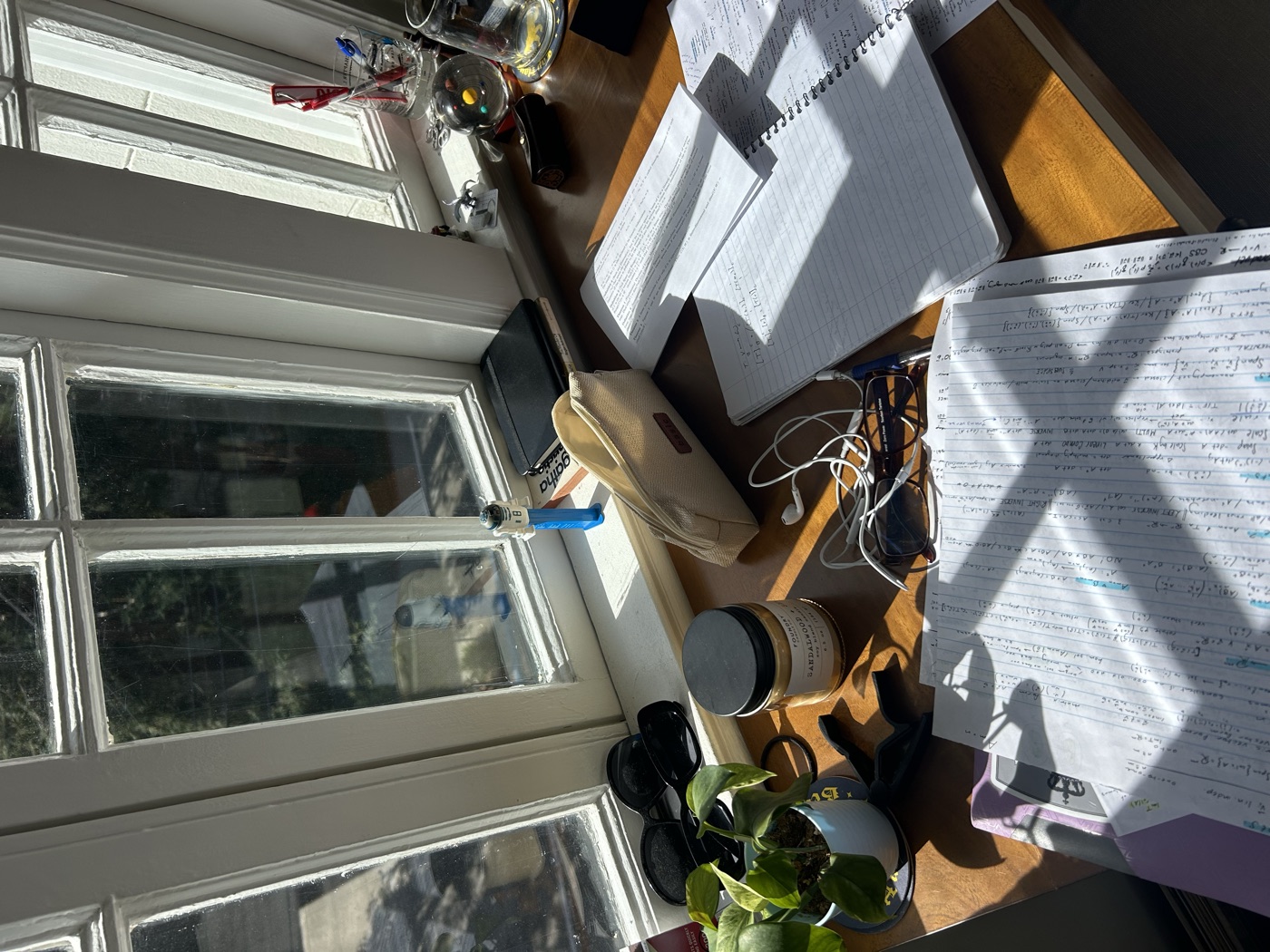 A desk covered in handwritten notes in afternoon sun